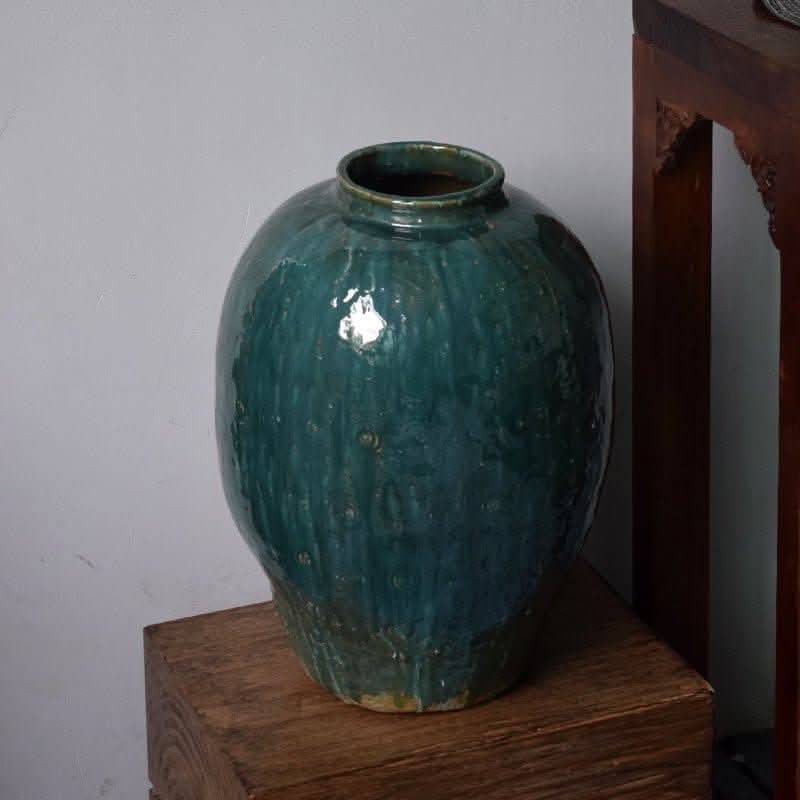 Rustic distressed rounded vase with dark green blue glaze, circular engraved pattern.