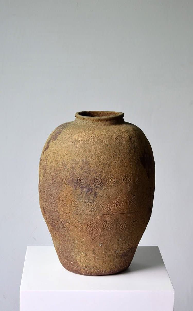 Rustic distressed rounded vase with engraved circular pattern in a dark green-blue glaze.