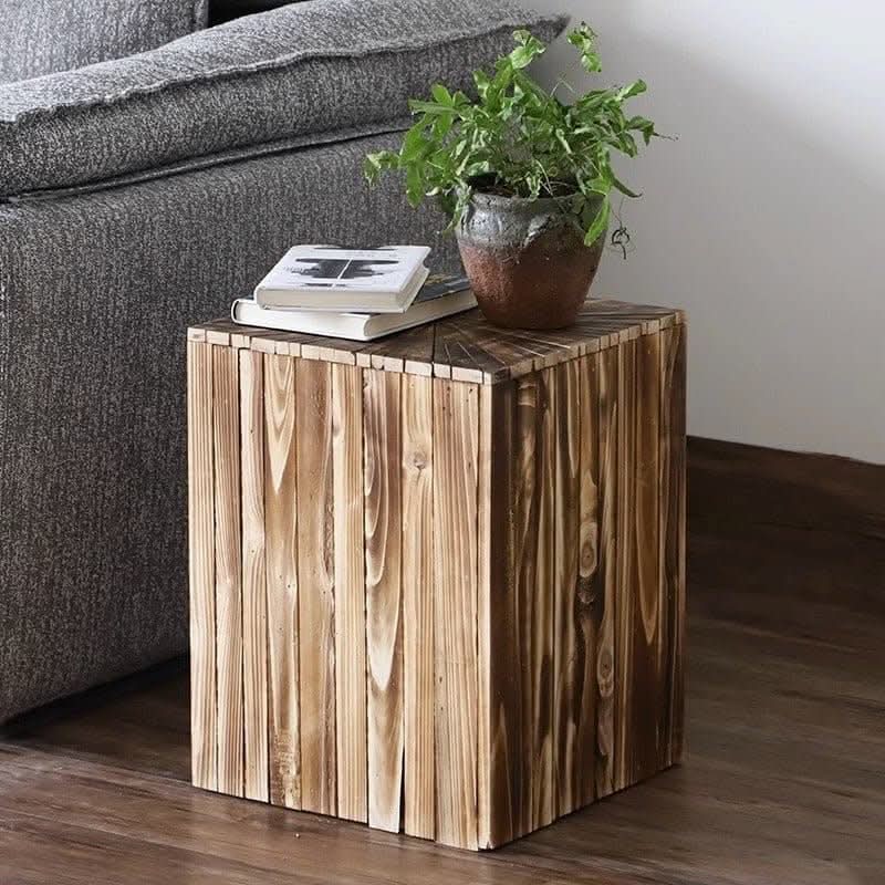Rustic Geometric Board Stool beside gray sofa, holding books and plant.