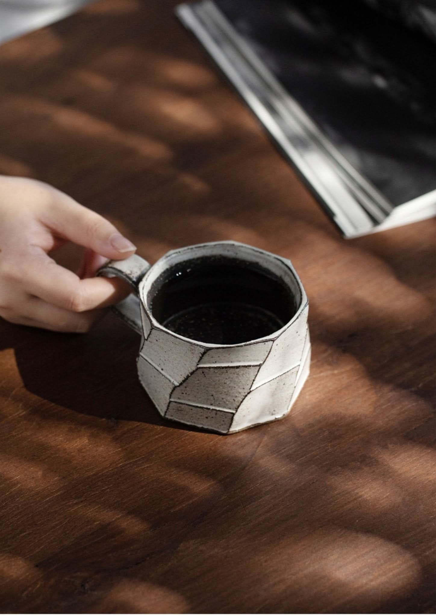 Hand-thrown Japanese stoneware mug, white glazed geometric design, on wooden table.