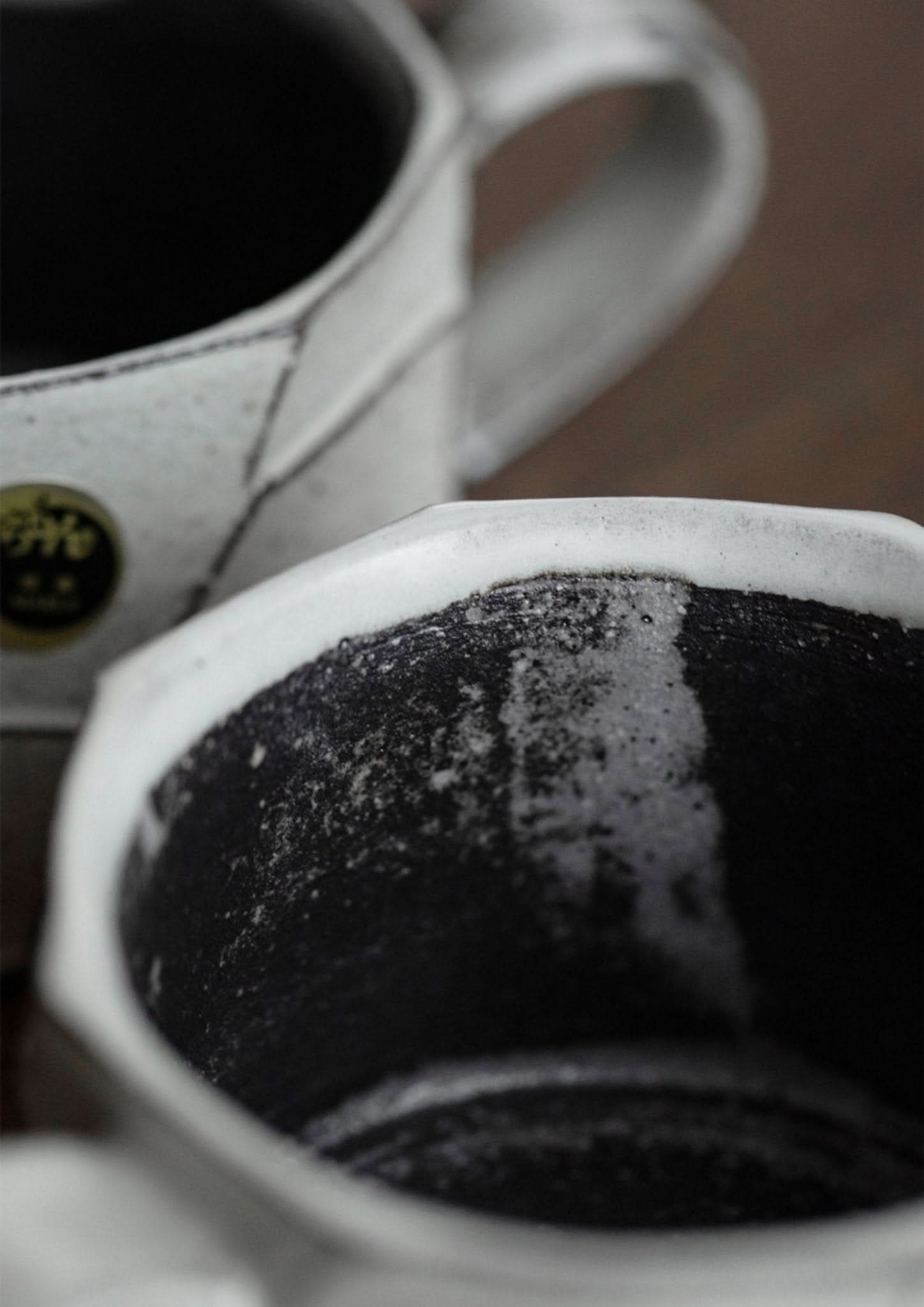 Rustic hand-made carved white stoneware mug, black interior, Japanese ceramic pottery.