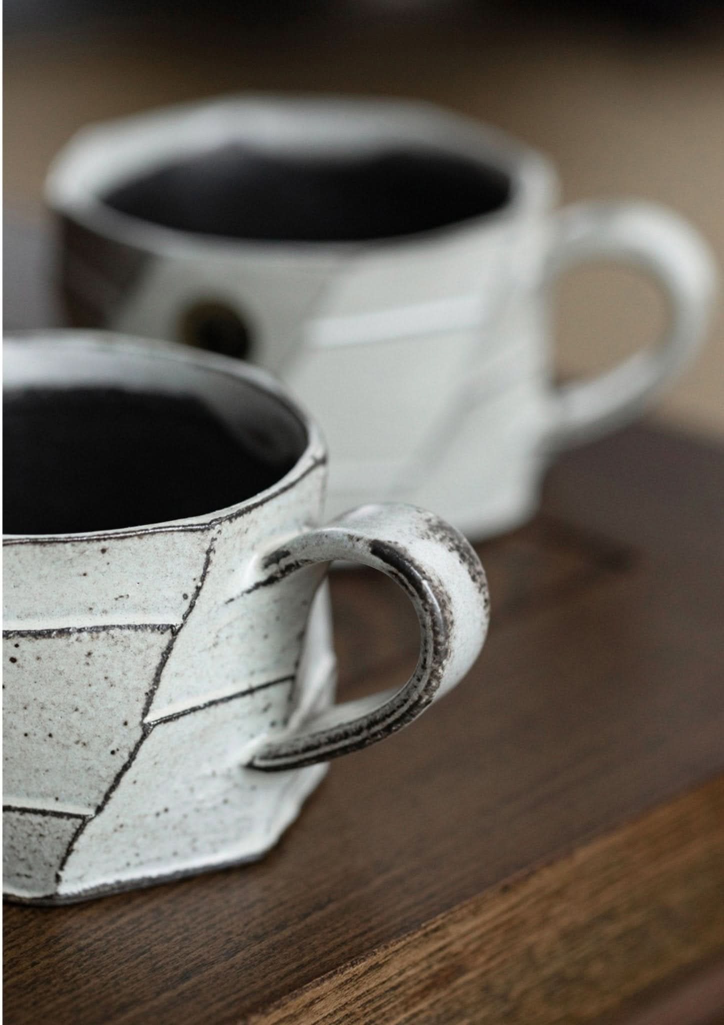 Rustic hand-made carved white stoneware mug, imported from Japan, on a wooden surface.