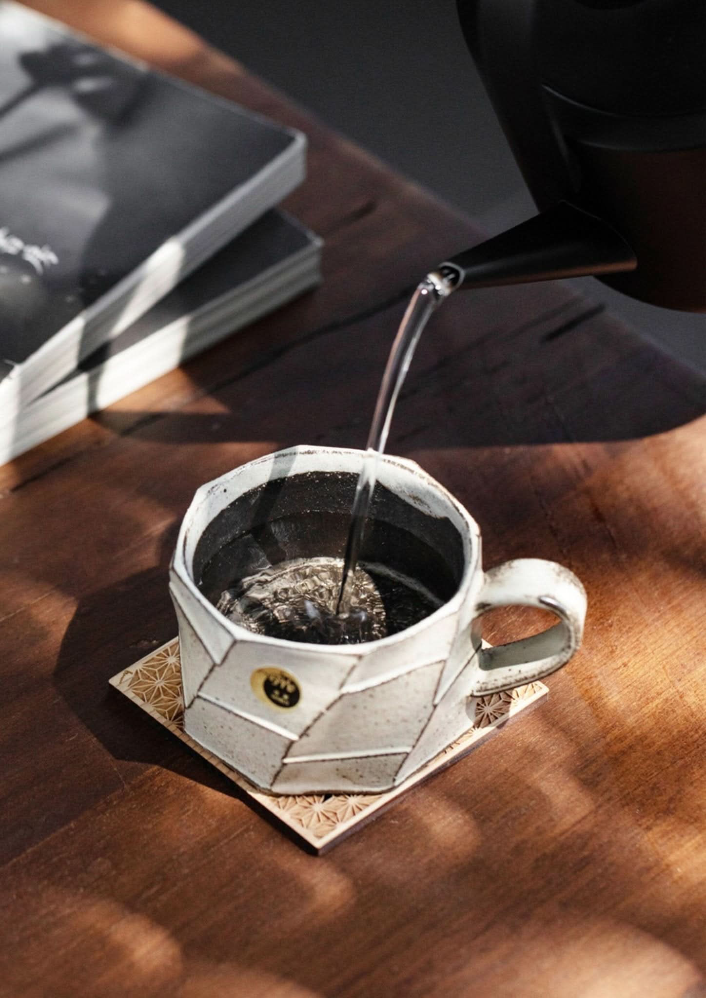 Rustic hand-thrown stoneware mug from Japan, glazed white with carved geometric design, on wooden table.