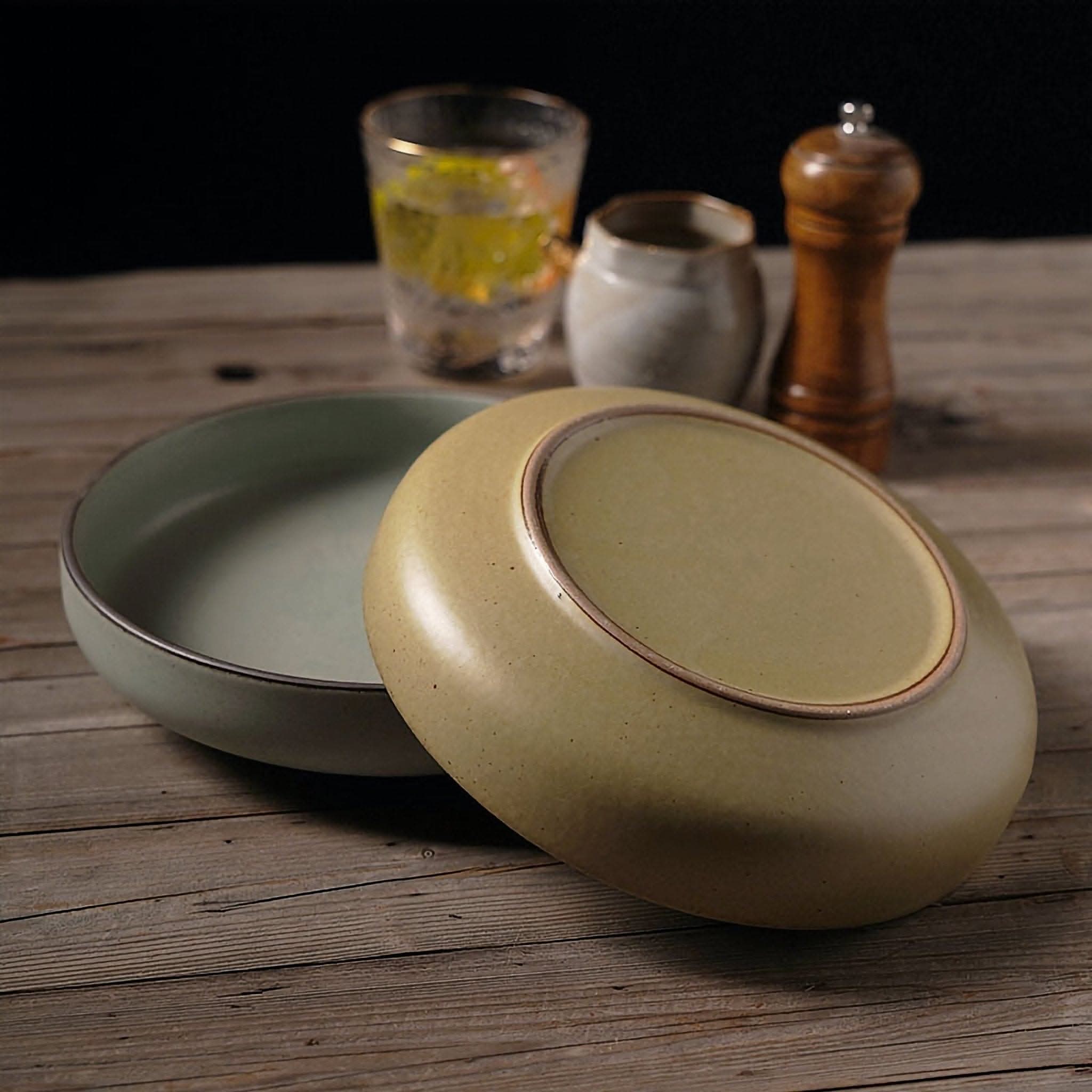 Shallow plates with earthy colors, ceramic dishes, salad bowl, on a wooden table.