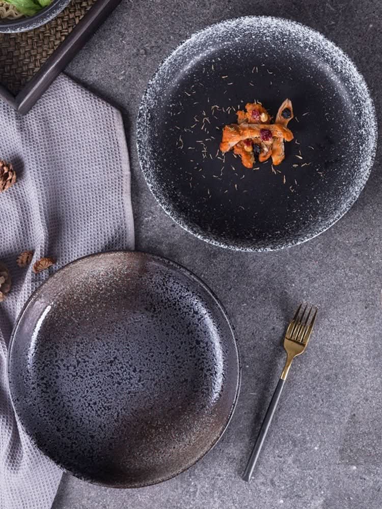 Gradient ceramic shallow plates with speckled finish, a salad bowl and fork.