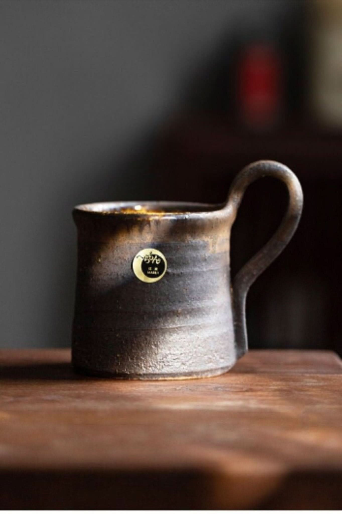 Rustic Shiraku-yaki stoneware mug, handmade in Japan, with a glazed finish on a wooden surface.