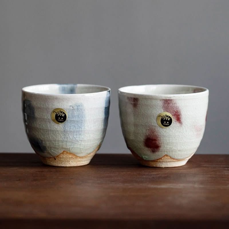 Two Shiraku-Yaki tea cups, Japanese handmade ceramic with ice cracked glaze, on wood.