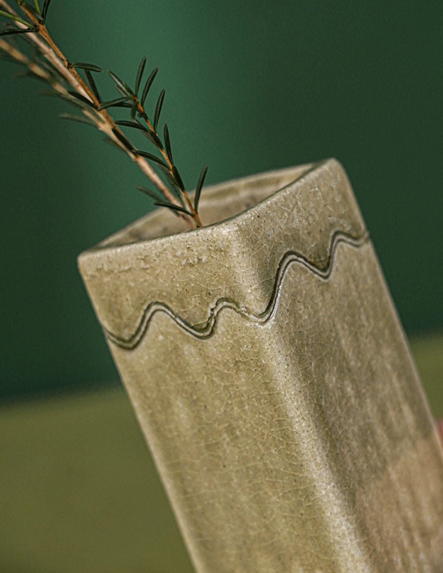 Shigaraki ceramic vase, beige stoneware with wavy detail, holding a green sprig.