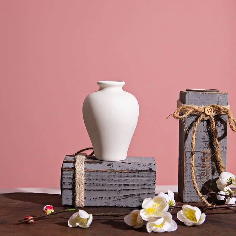 Small Ceramic White Bud Vase on rustic wood block with flowers.