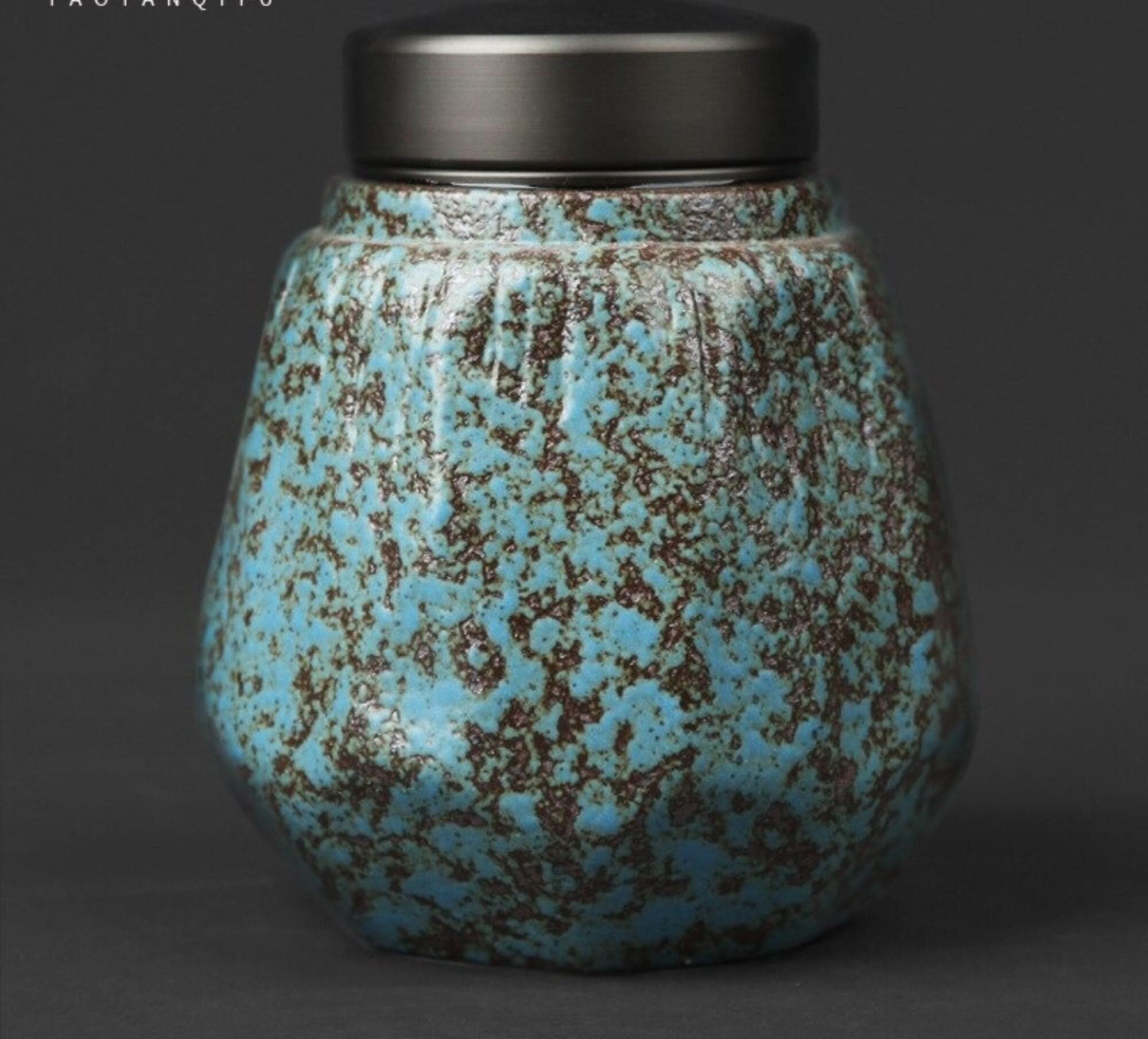 Small stoneware sealed tea can with speckled blue and brown glaze, featuring a dark metal lid.