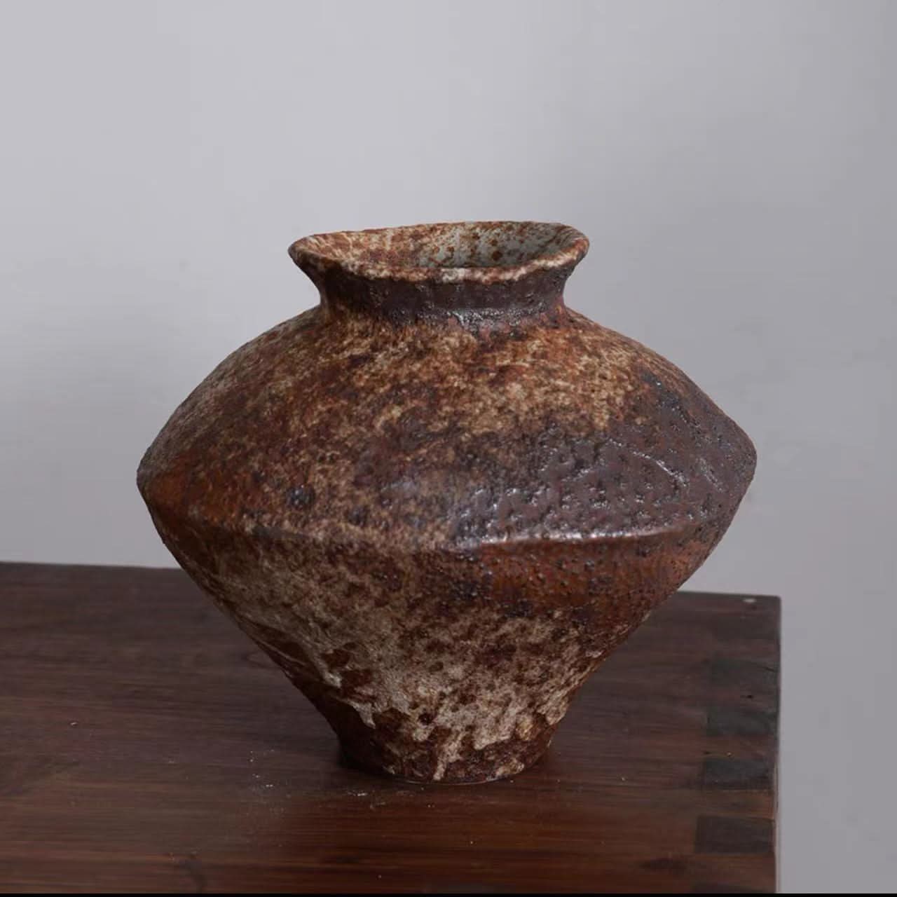 Rustic Wabi Sabi ceramic vase for flowers in earthy brown tones, displayed on a wooden surface.