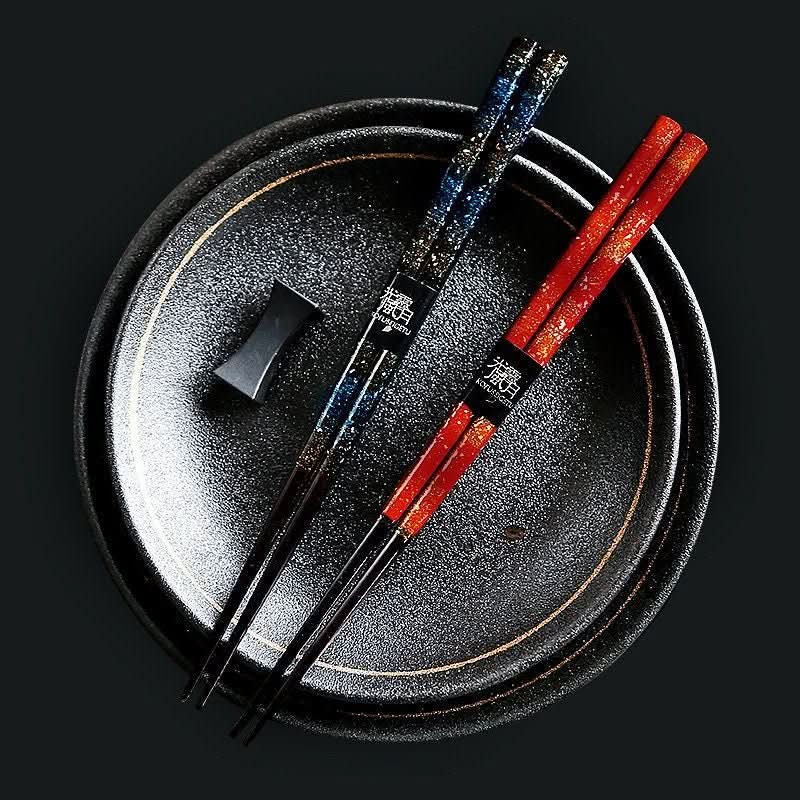 Japanese Chopstick Set Handmade Lacquered: red & blue chopsticks on textured dark plate.