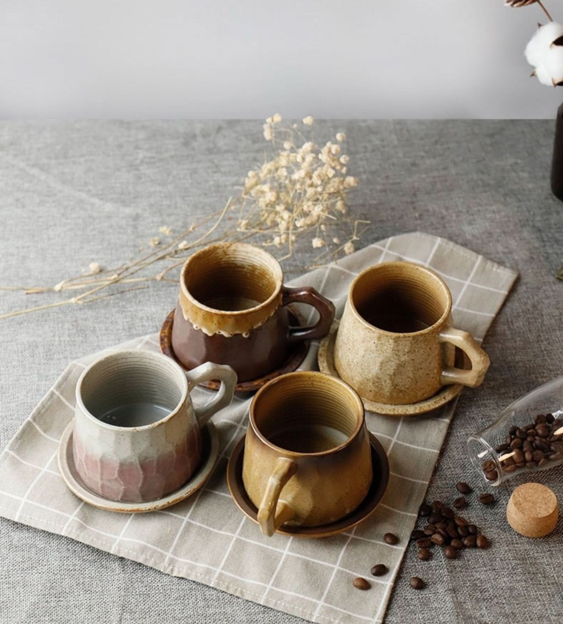Four rustic Stoneware Mugs 10.14oz with saucers on a checkered cloth.