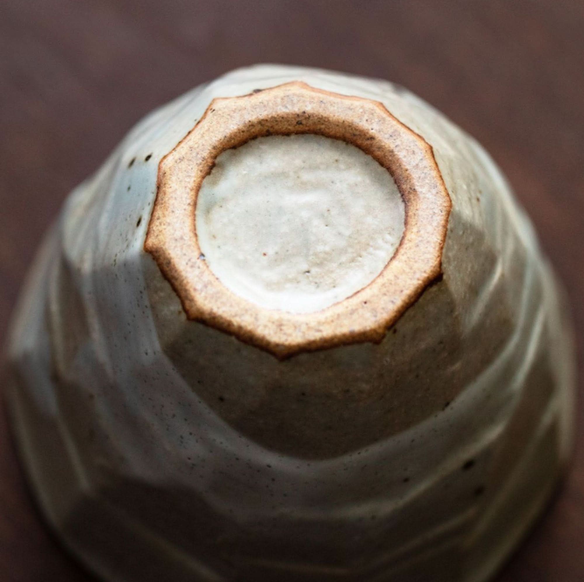 Close-up of the base of a Japanese cup, ceramic, off-white with brown rim.