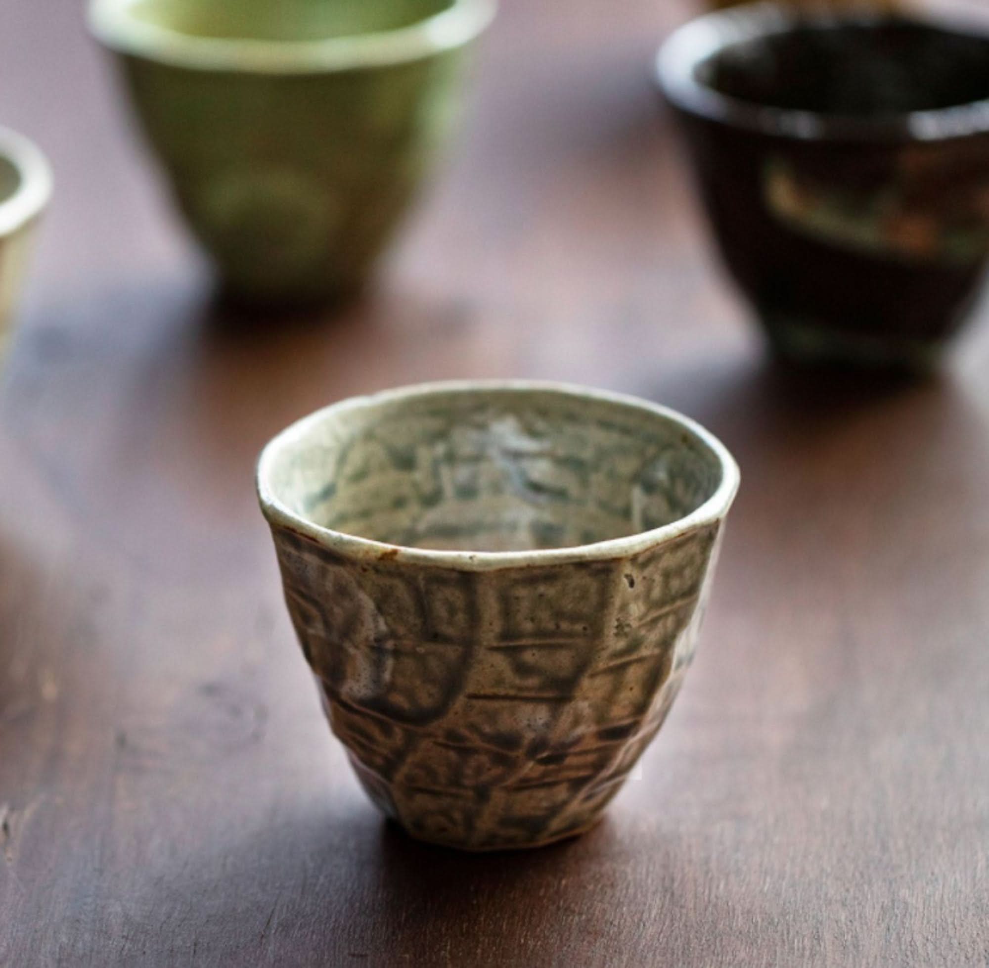 Textured ceramic Japanese Cups Set 9.4oz in earthy tones on a wooden surface.