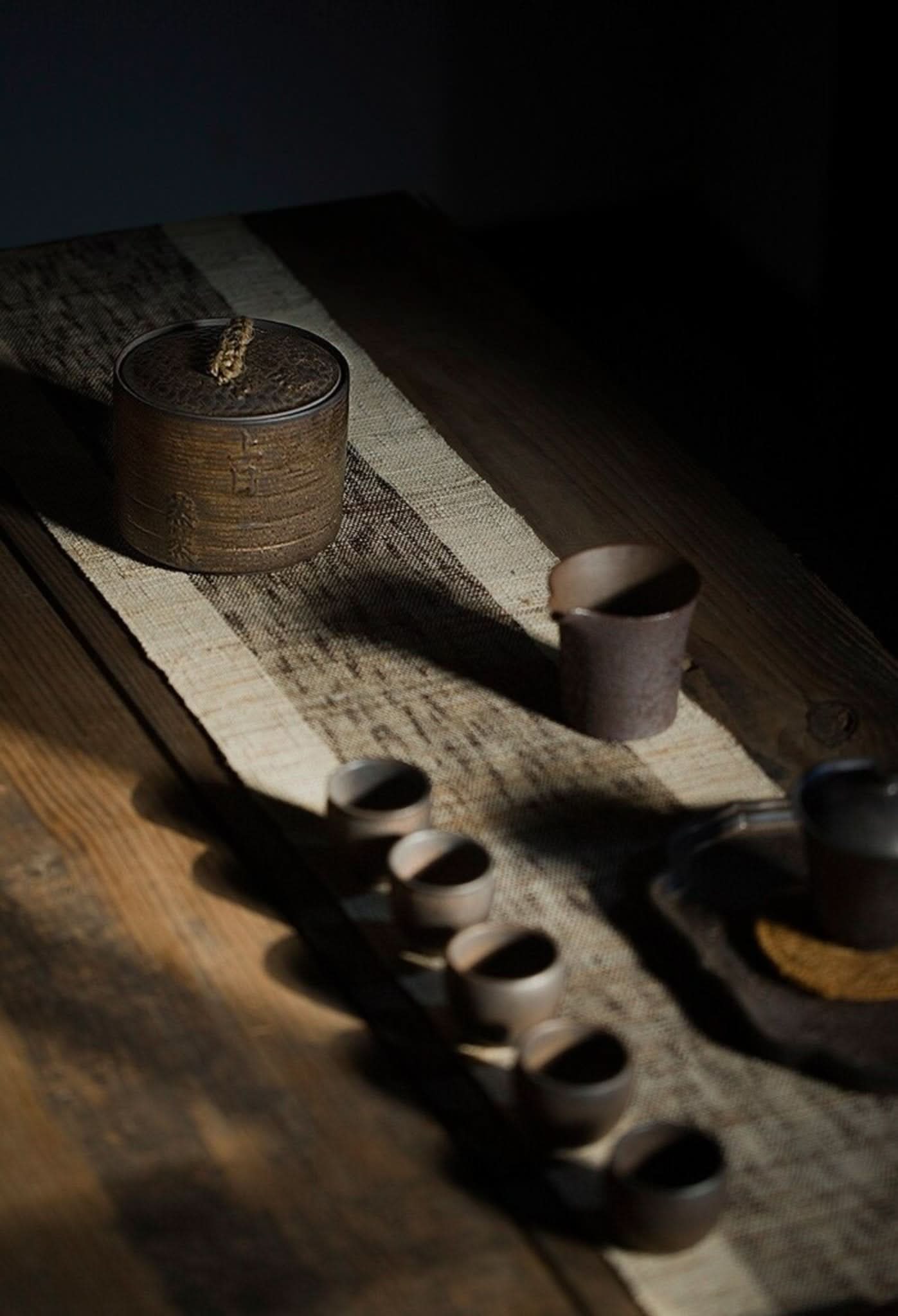 Japanese Style Ceramic Tea Ceremony Jar with small cups on a wooden table.