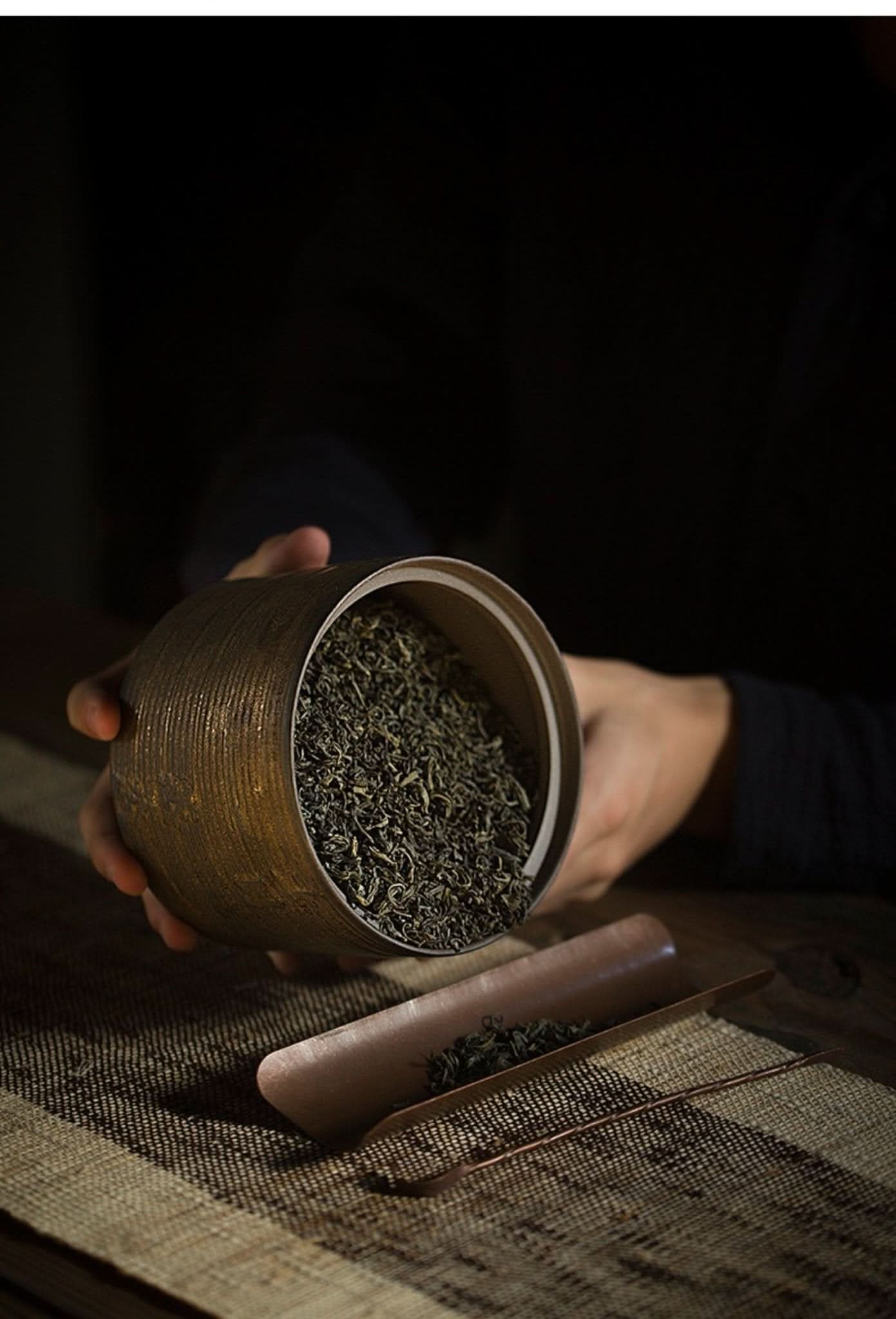 Japanese style ceramic tea ceremony jar with dry tea leaves, bamboo scoop.