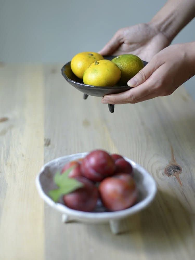 Tripod Stoneware Ceramic Irregular Fruit Bowl holding oranges and plums on wood table