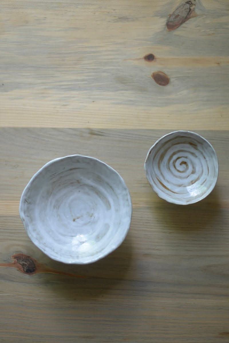 Two Tripod Stoneware Ceramic Irregular Fruit Bowls with swirled patterns on a wooden table.