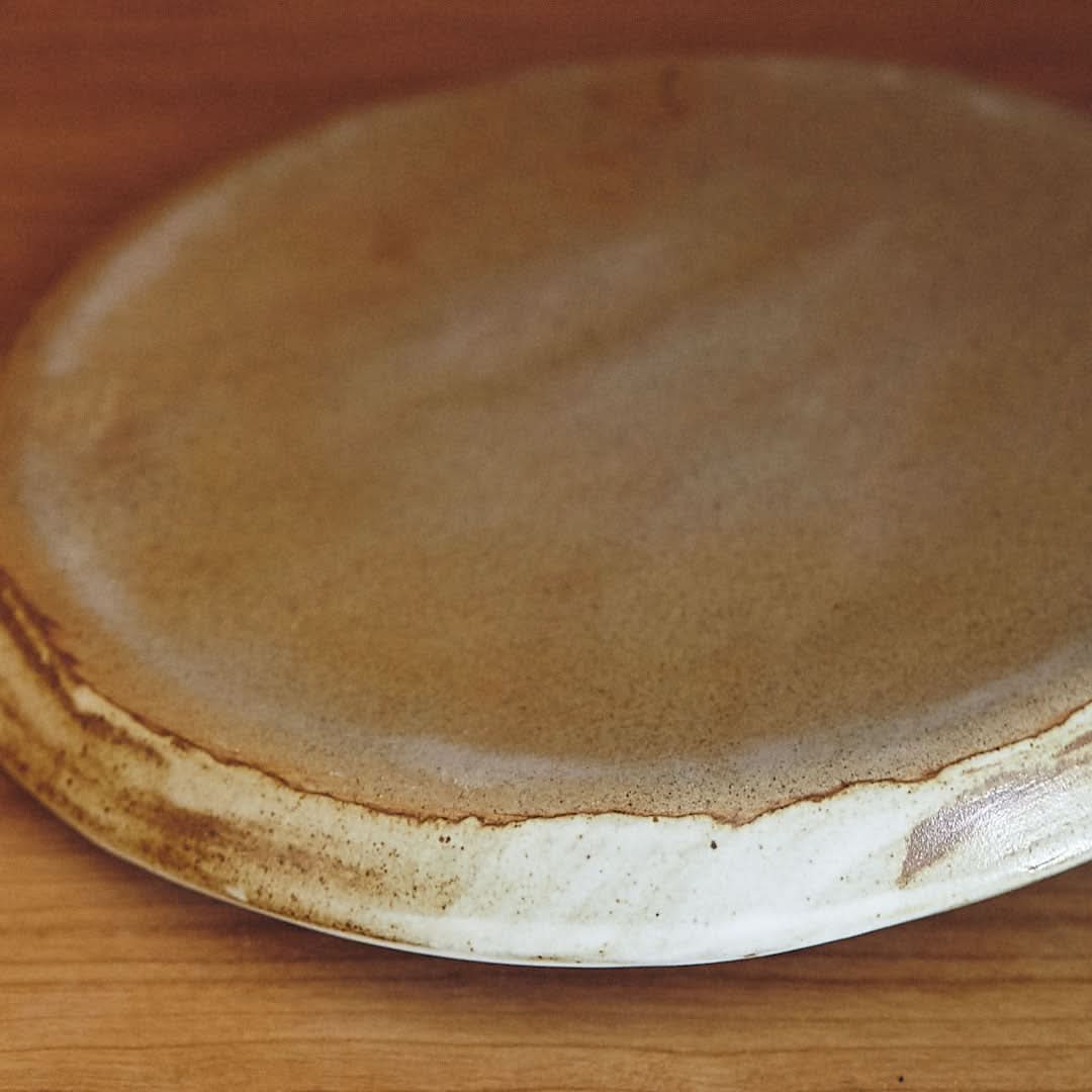 Stoneware plate, white glaze, brown edge, durable.