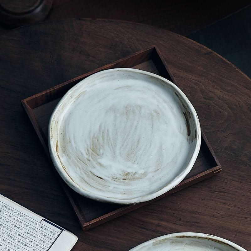 Stoneware Plates With White Glaze, rustic textured white ceramic on dark wood surface.