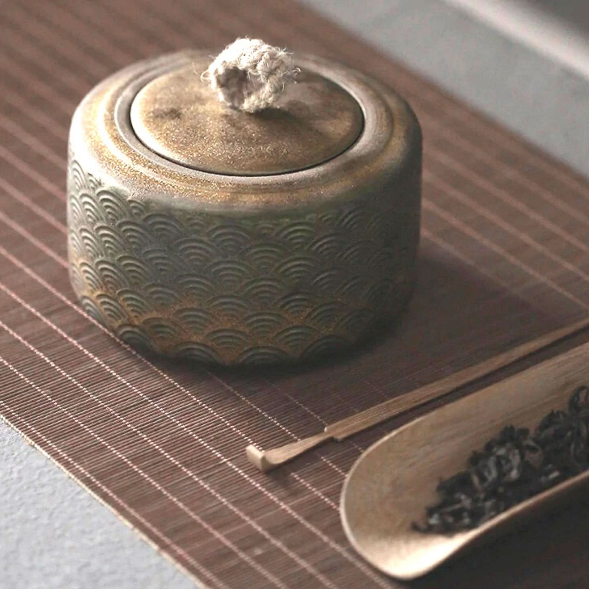 Vintage Japanese tea jar with textured waves, on bamboo mat.