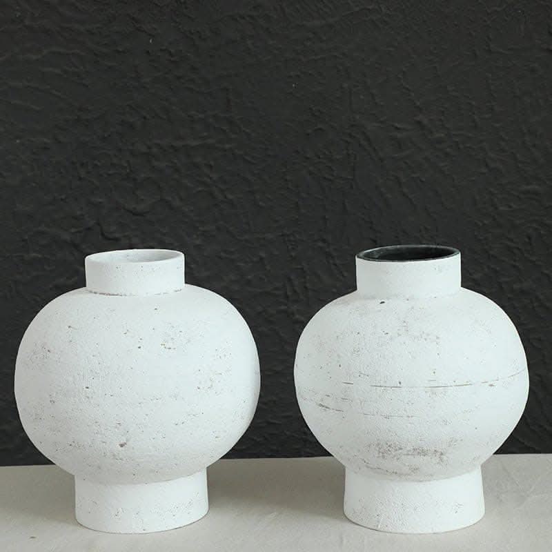 Wabi-sabi white clay pot, round, with tight opening, set against textured black background.