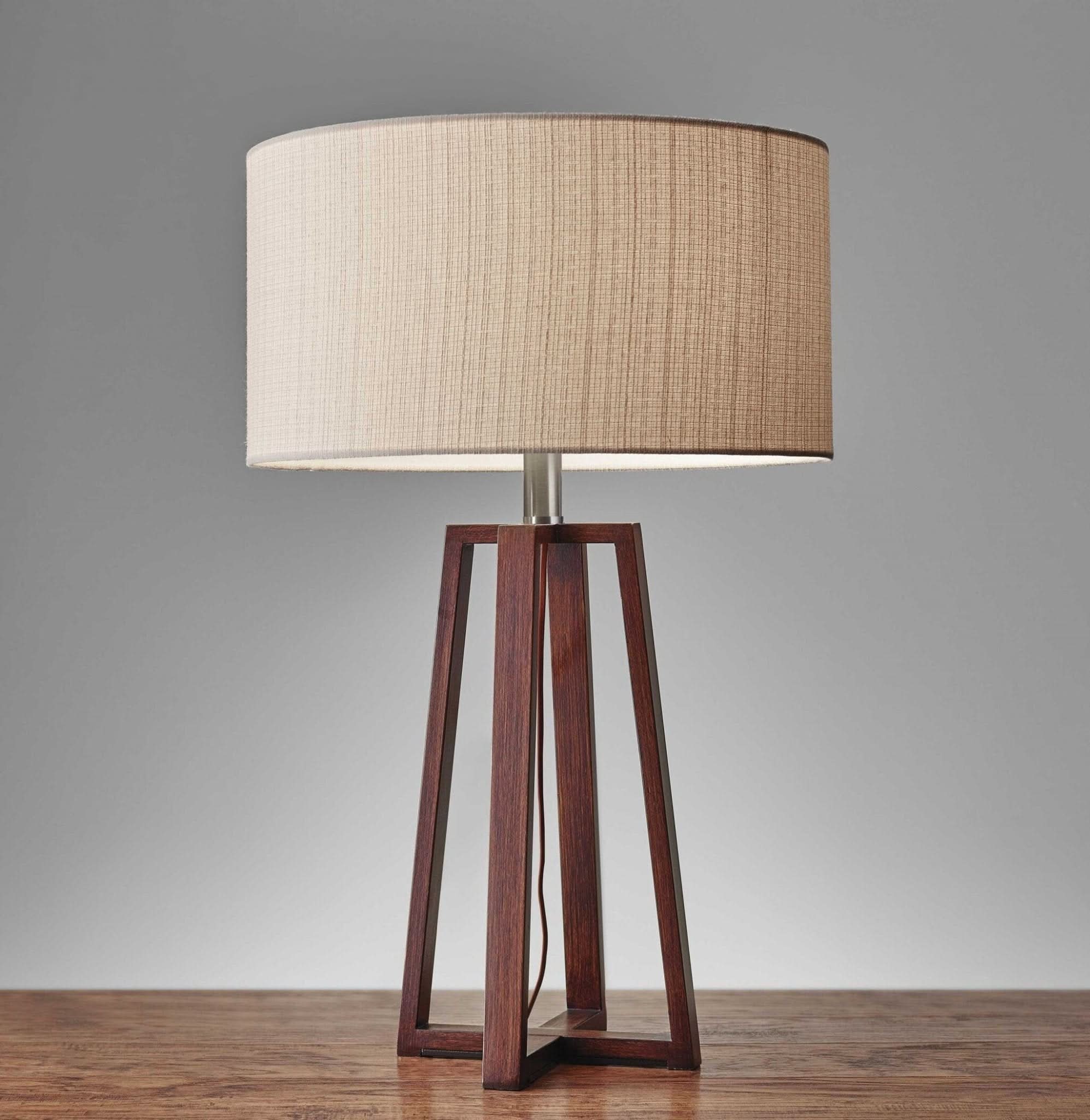 Walnut wood table lamp with beige linen fabric shade on wooden surface.