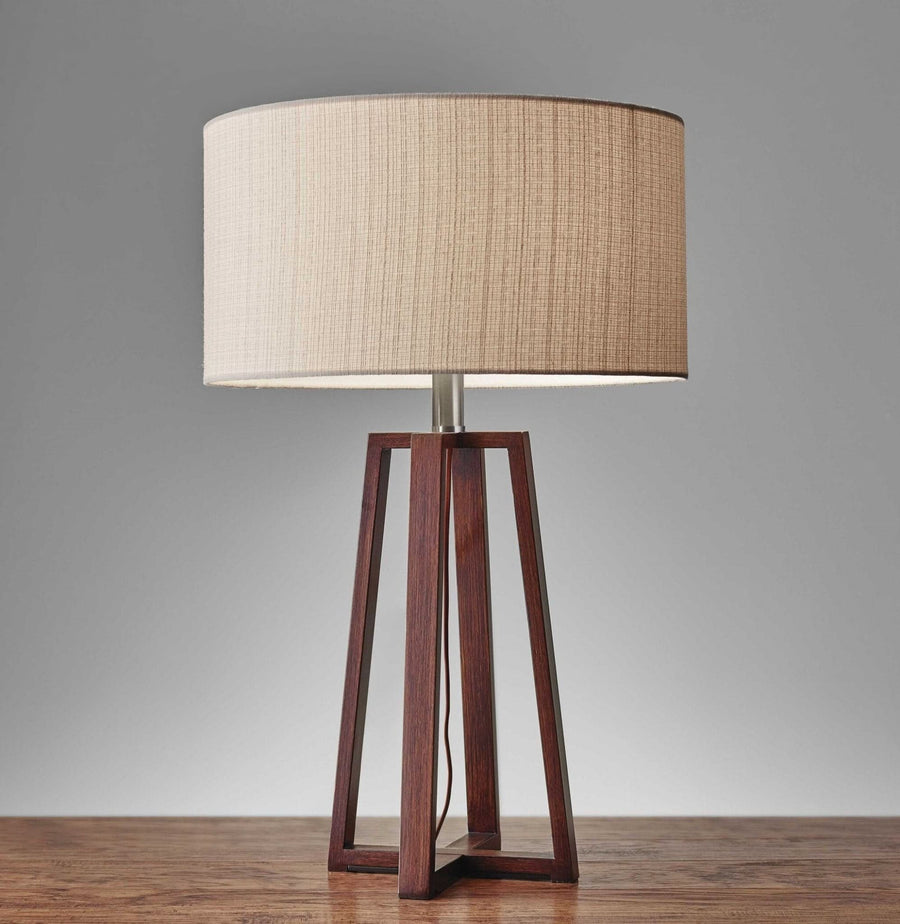 Walnut wood table lamp with beige linen fabric shade on wooden surface.