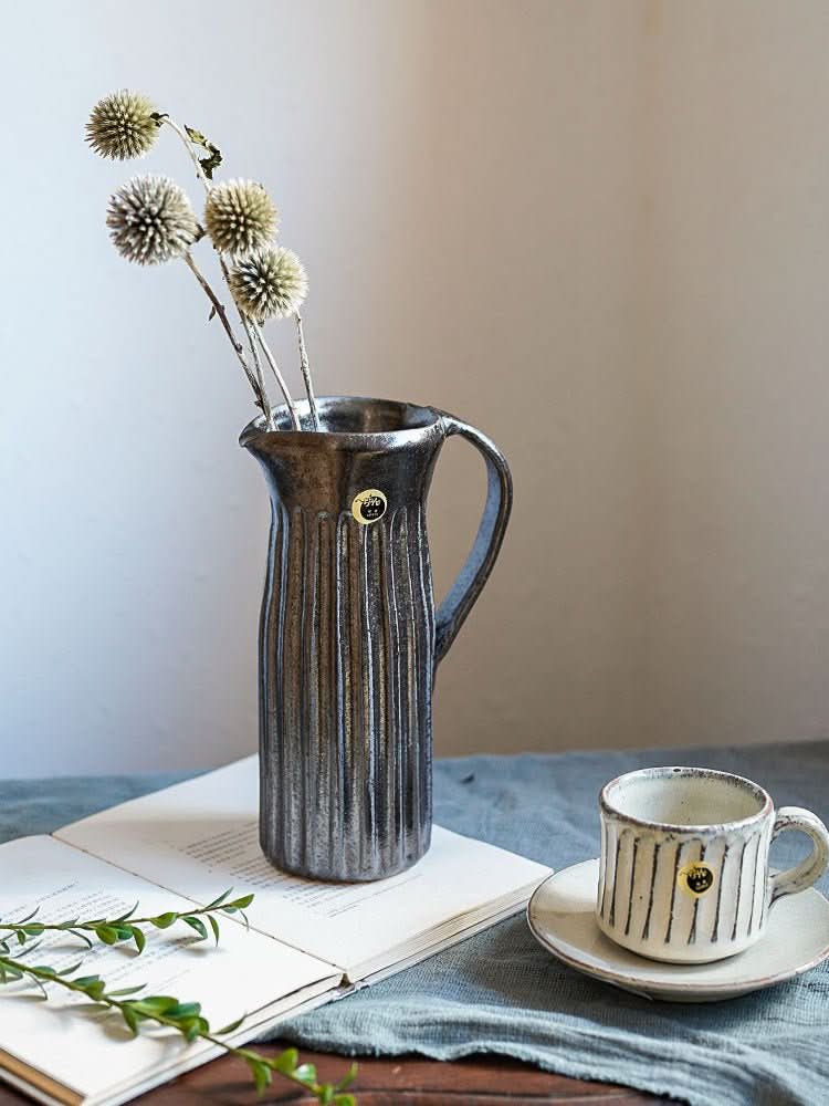 Water Cylindrical Black Glaze Carved Pattern Vase with dried flowers on a table.