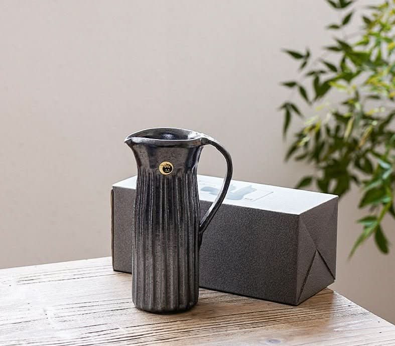 Water Cylindrical Black Glaze Carved Pattern Vase on a wooden table with a gift box, home decor.