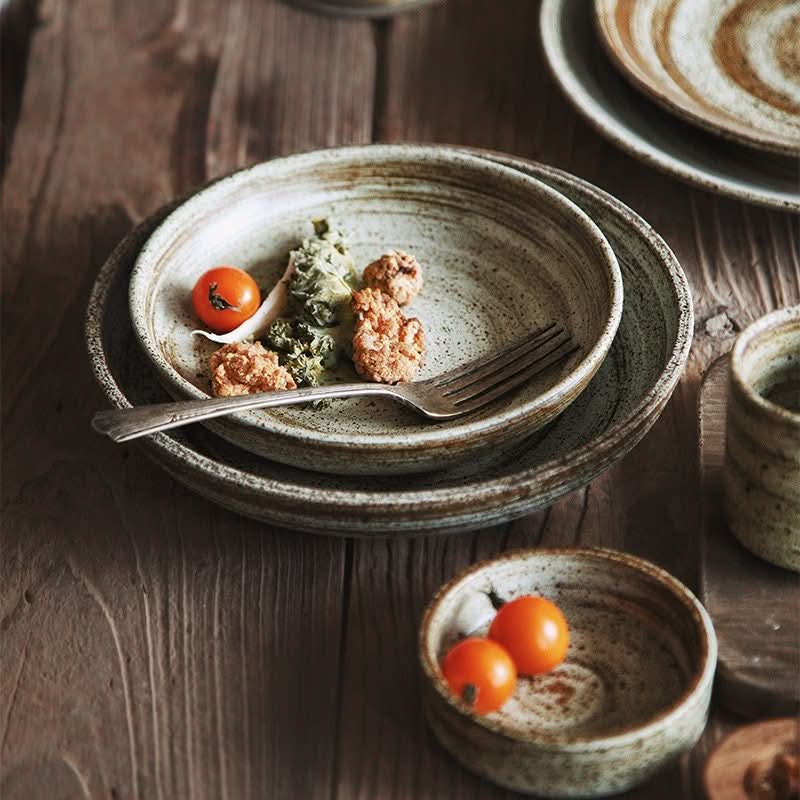 Rustic dinnerware, white & brown spiral glaze bowls with fork, cherry tomatoes, and garnishes on wooden table.