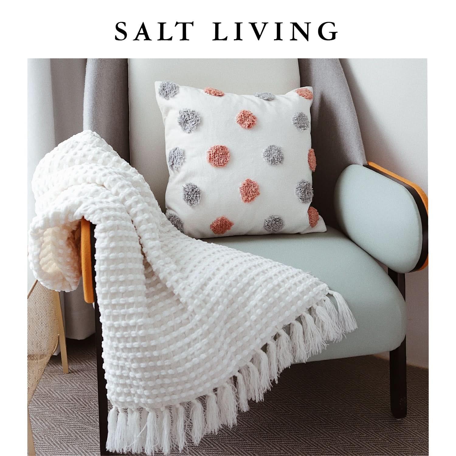 White chenille hand-loomed mud cloth blanket with tassels draped on a light blue chair.