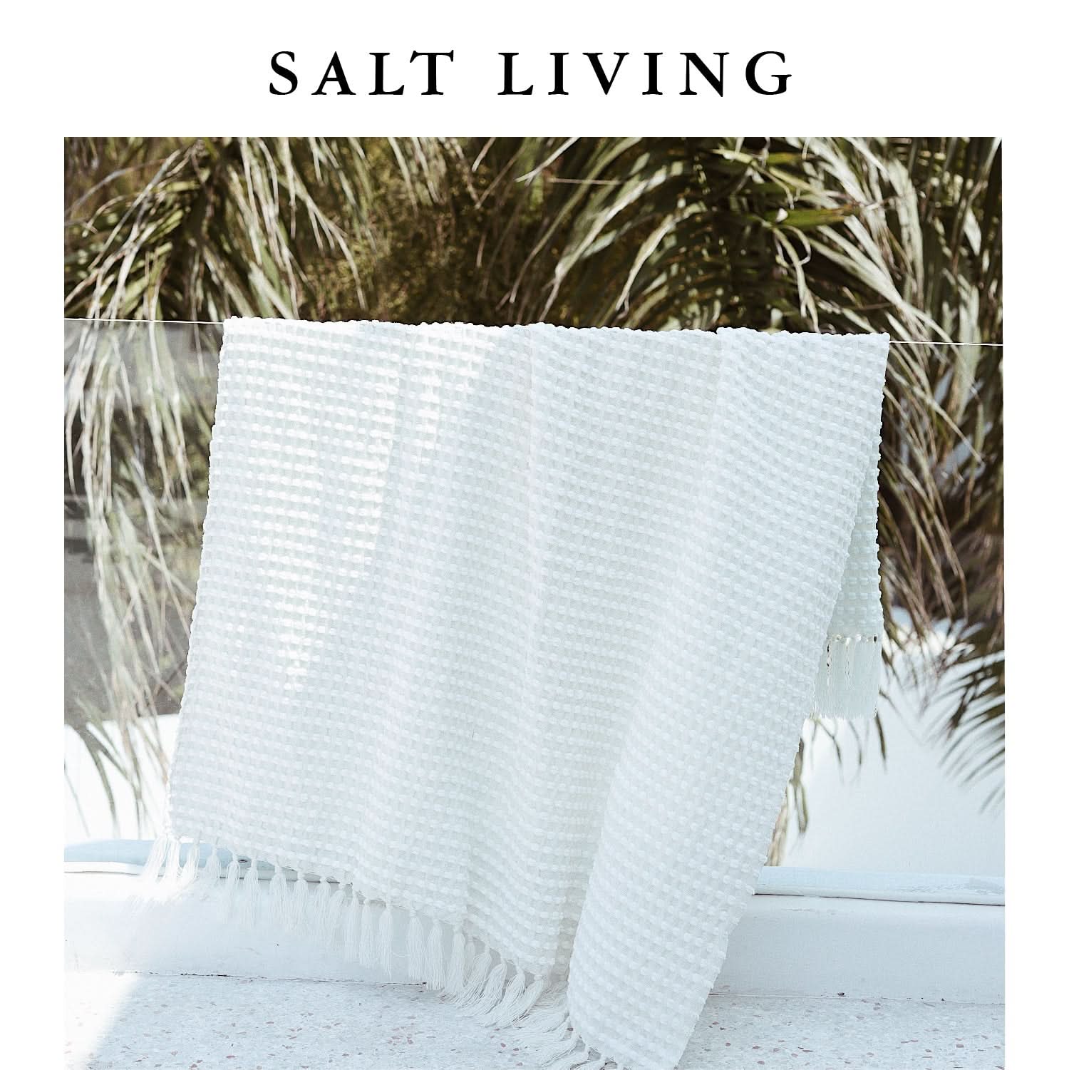 White chenille hand-loomed mud cloth blanket with fringe detail, draped outdoors.