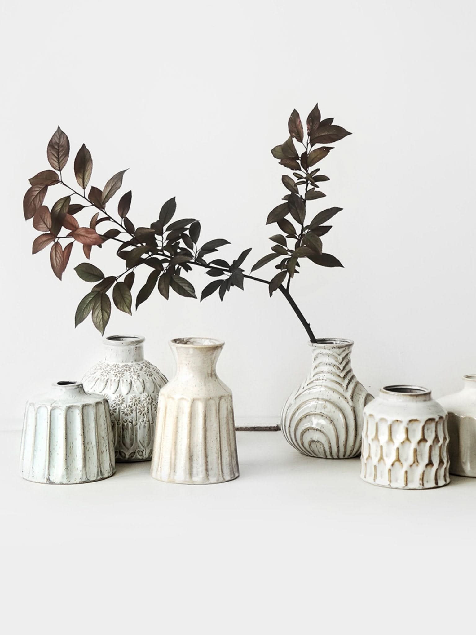Collection of small white ceramic vases with textured surfaces, home decor.
