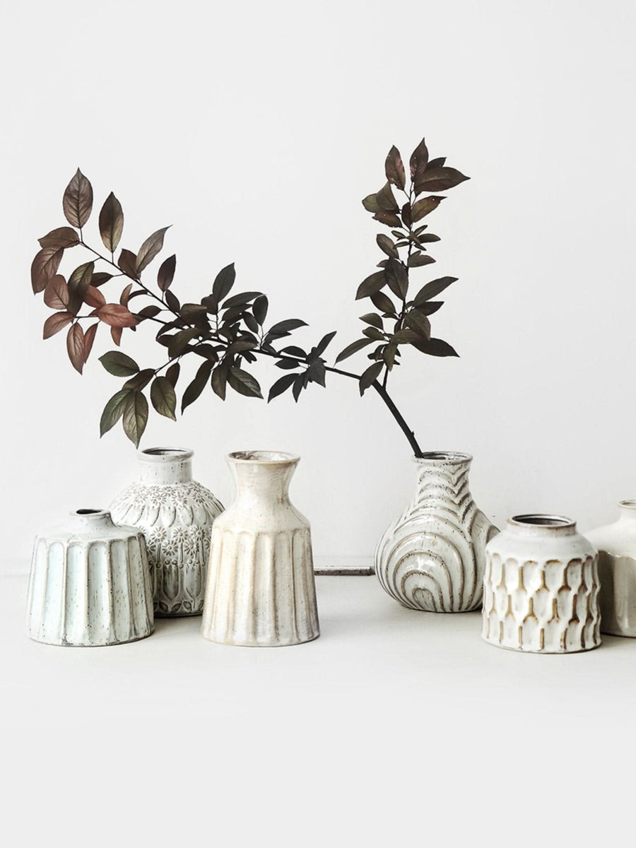 Collection of small white ceramic vases with textured surfaces, home decor.