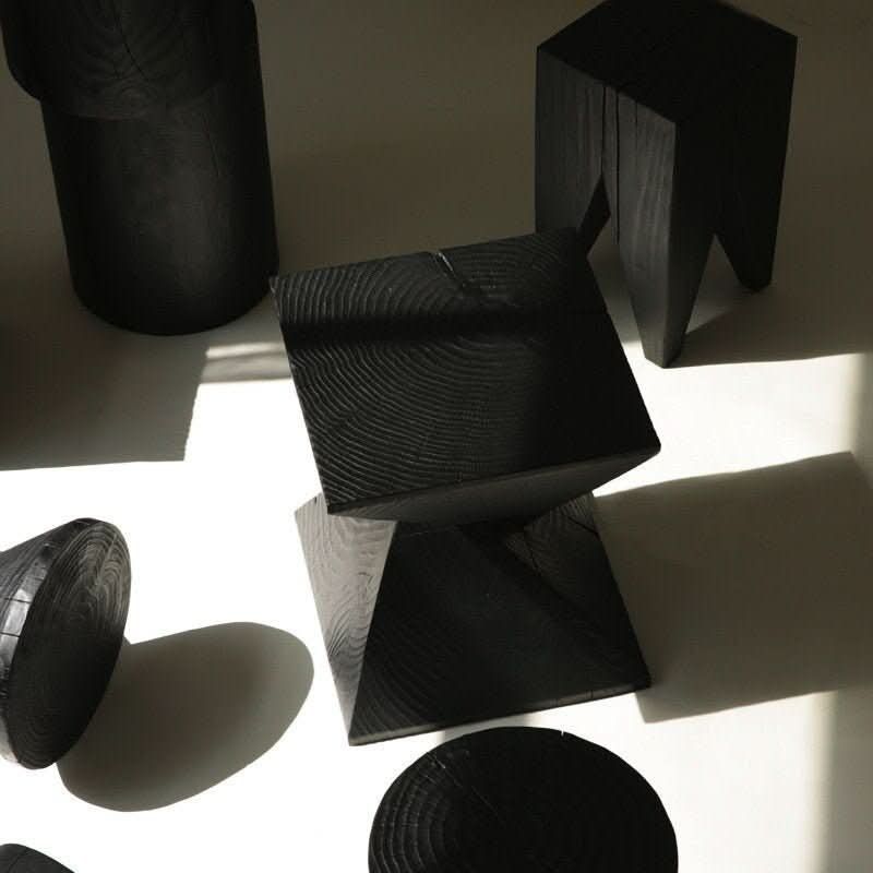 Black wood stool with visible grain, arranged as home decor.