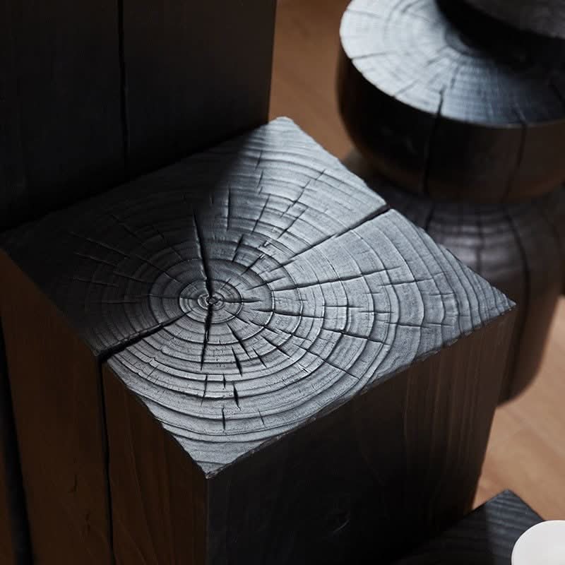 Textured black wood stool with visible grain, modern home decor accent.